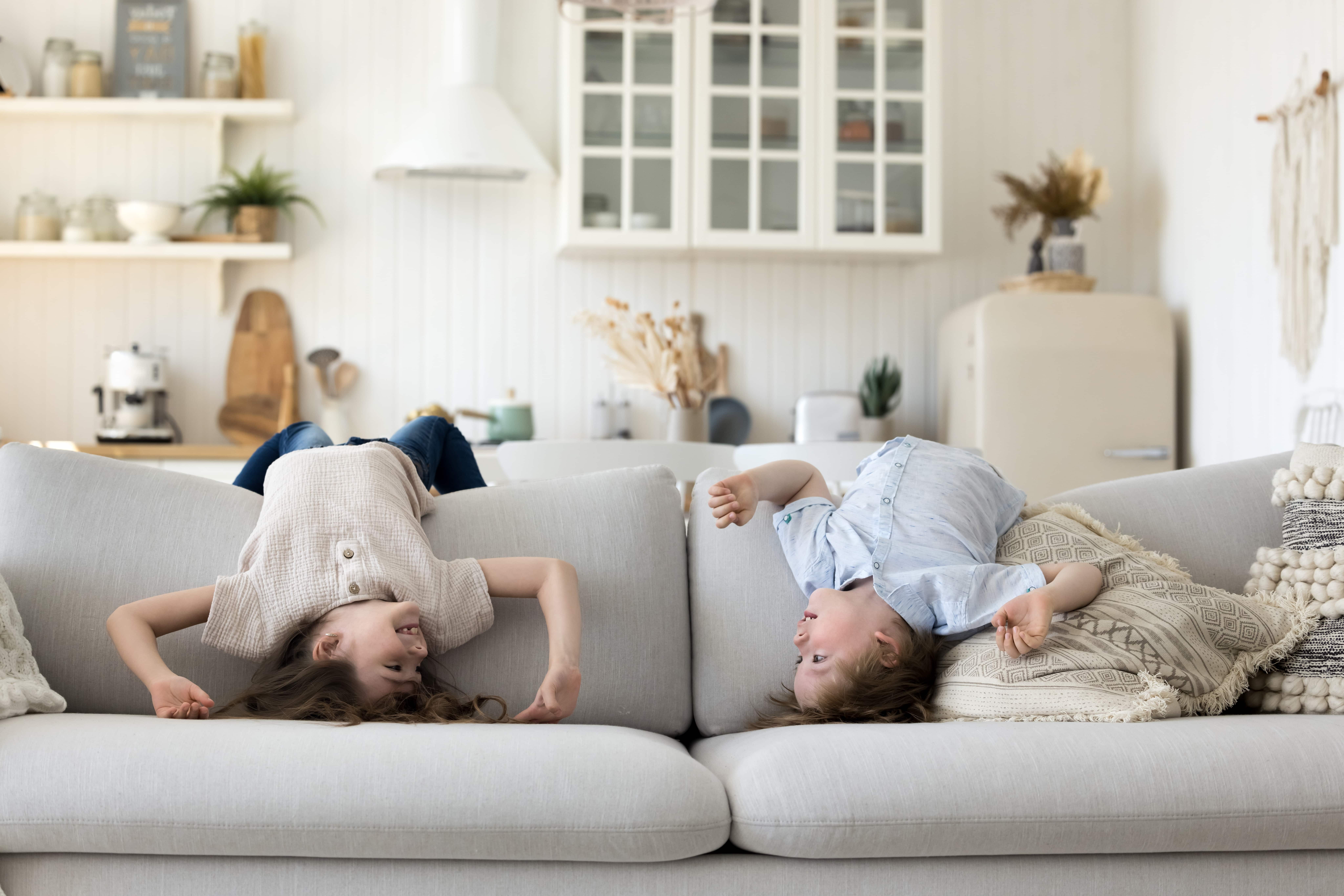 Two happy children upside down on a couch. To symbolise the outcome of learning how to co parent successfully