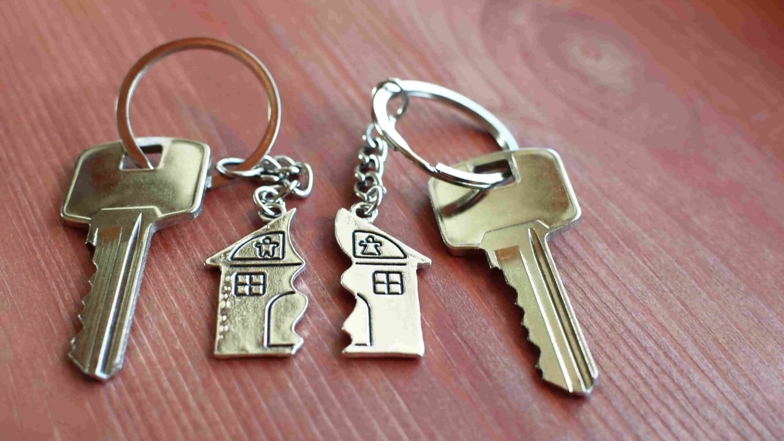 Pendant of key ring in shape of house divided in two parts on wooden background, closeup view.Illustrating the concept of moving out upon a separation for our topic about who moves out when you separate