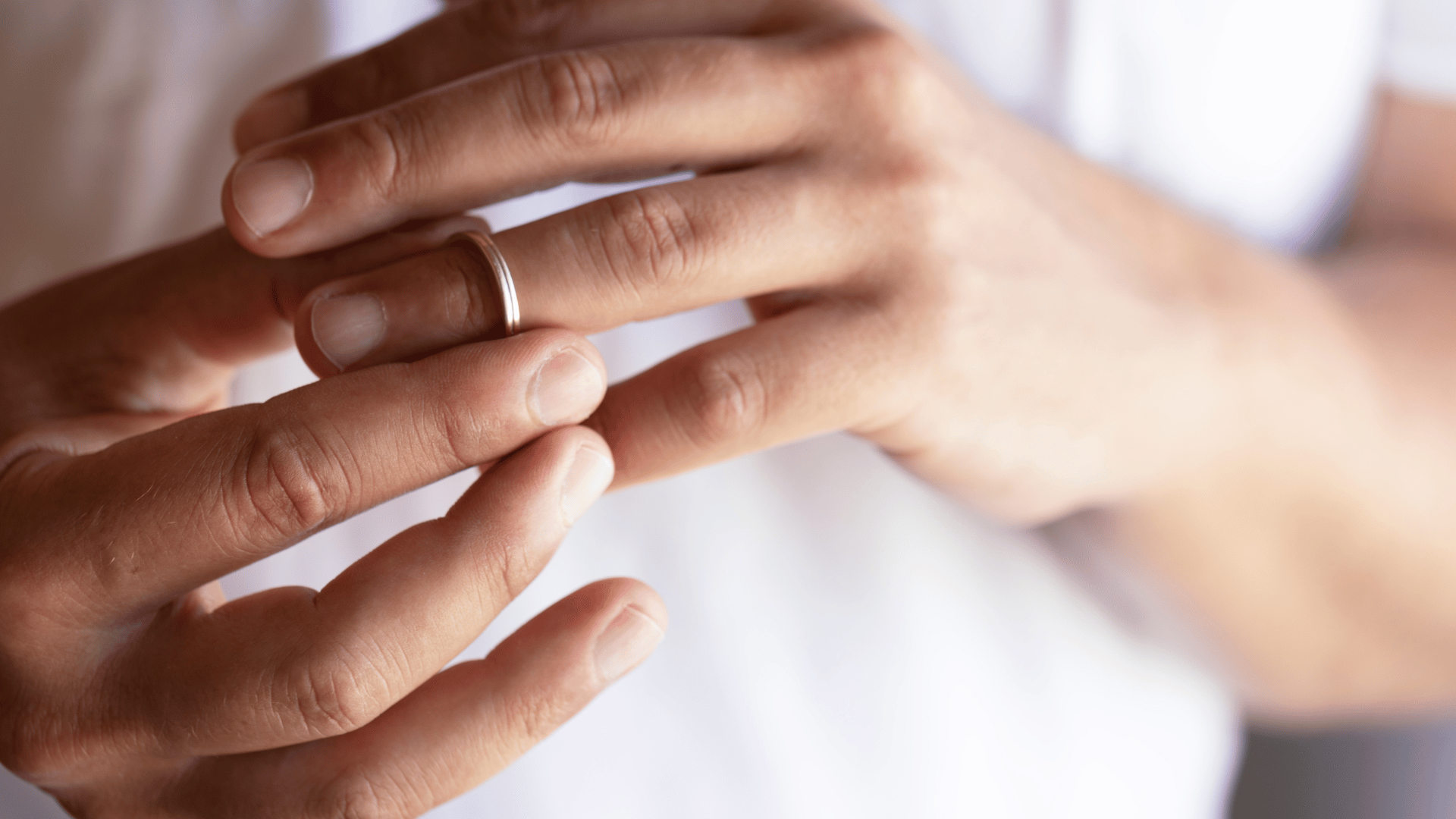 Person's hands removing wedding band to symbolise end of relationship. Family Lawyers Penrith. Family Solicitors Sydney. Family Lawyers Penrith.